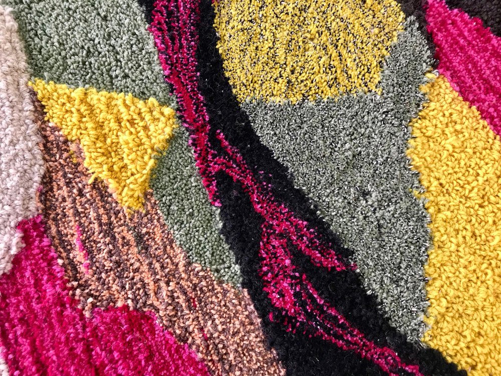 Tufted rug in maroon, yellows, greys